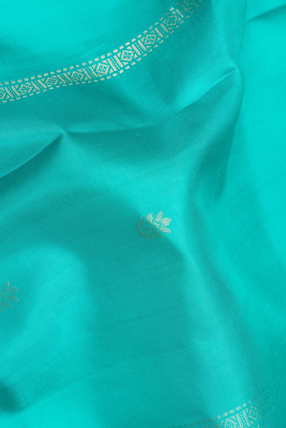 Close up of Pure Silk Turquoise Dual Tone Soft Saree with Zari Butta on the body and Zari Border.  displaying folds