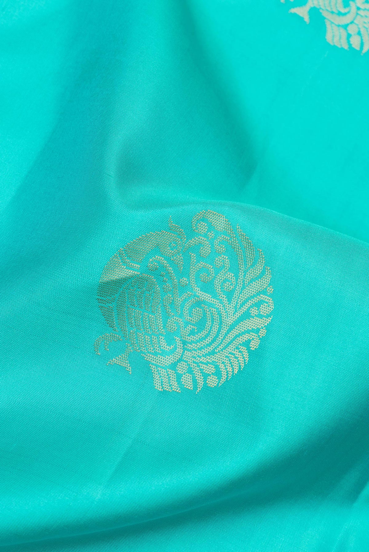 Close up of Pure Silk Turquoise Soft Saree with Zari Butta on the body and Zari Border.  displaying folds