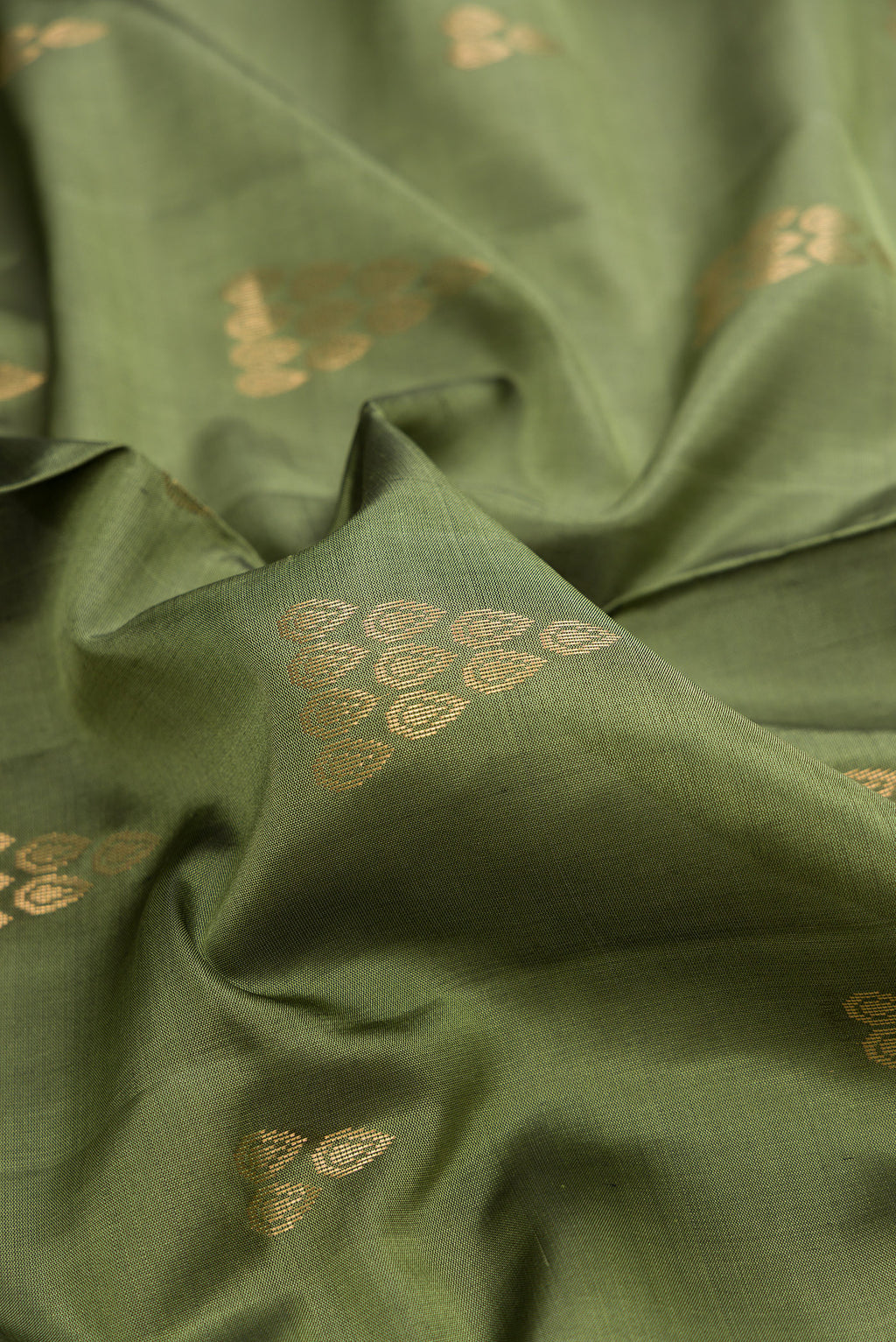 Close up of Pure Silk Olive Green Soft Saree with Zari Butta on the body and Zari Border.  displaying folds