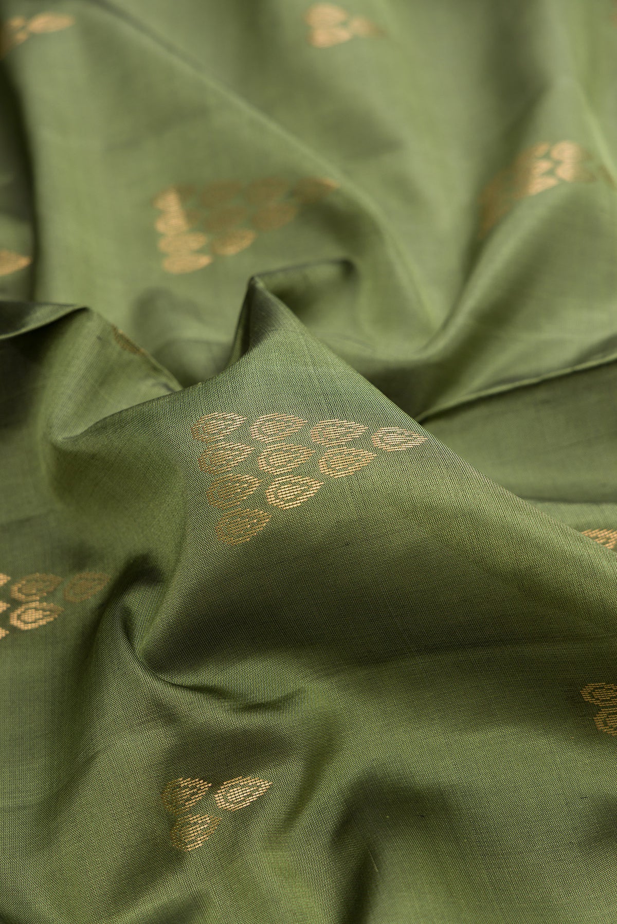 Close up of Pure Silk Olive Green Soft Saree with Zari Butta on the body and Zari Border.  displaying folds