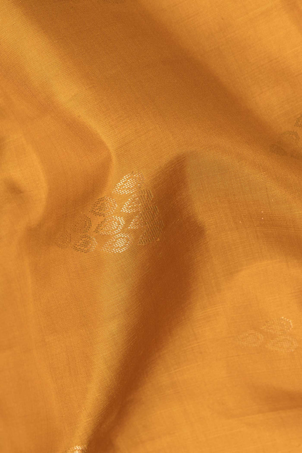 Close up of Pure Silk Mustard Soft Saree with Zari Butta on the body and Zari Border.  displaying folds