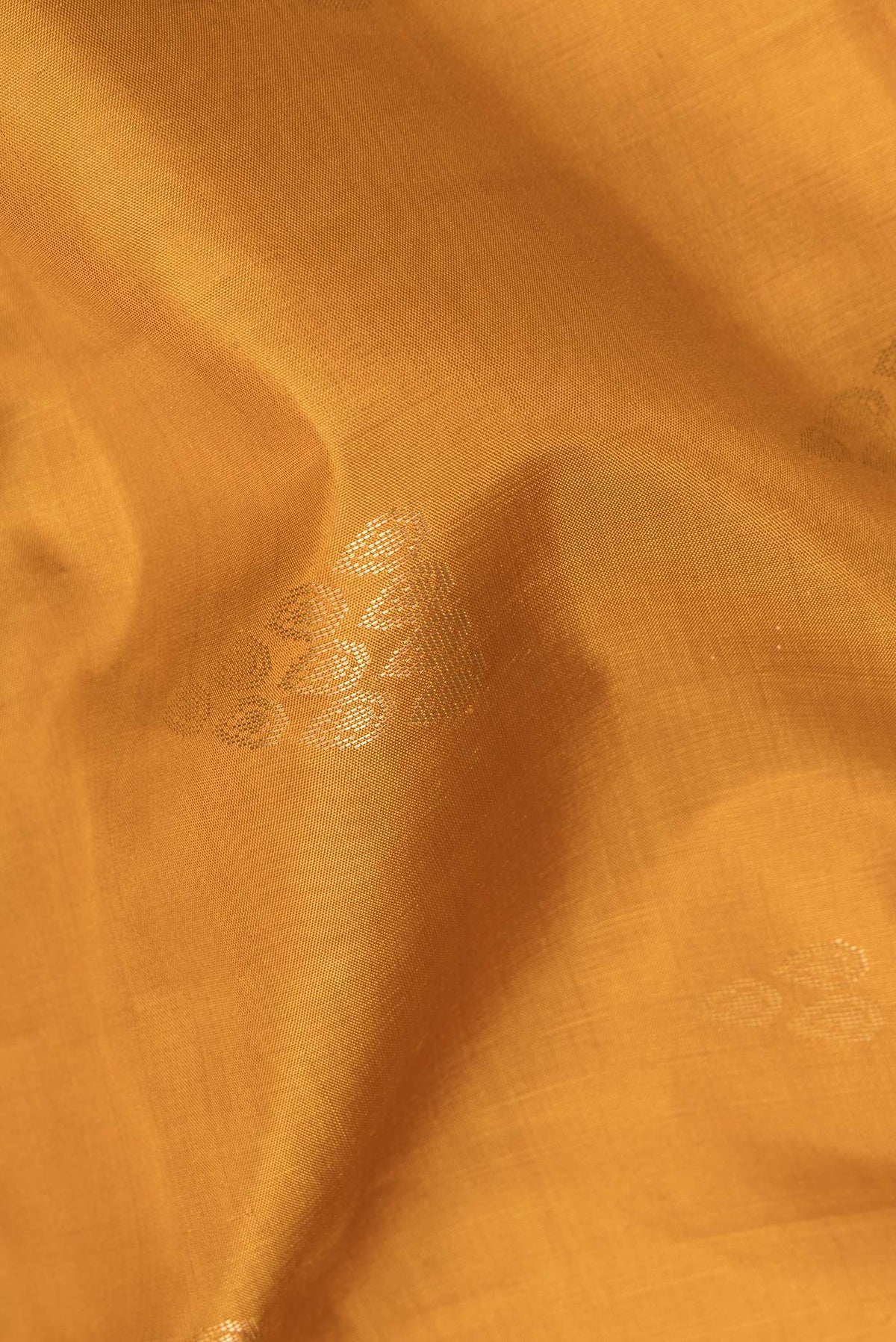 Close up of Pure Silk Mustard Soft Saree with Zari Butta on the body and Zari Border.  displaying folds
