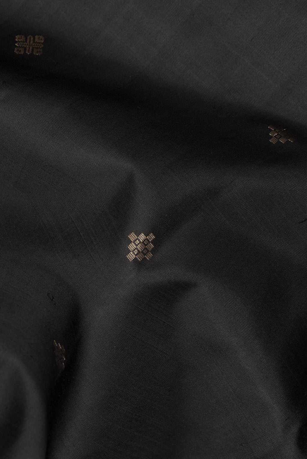 Close up of Pure Silk Black Soft Saree with Zari Butta on the body and Zari Border.  displaying folds