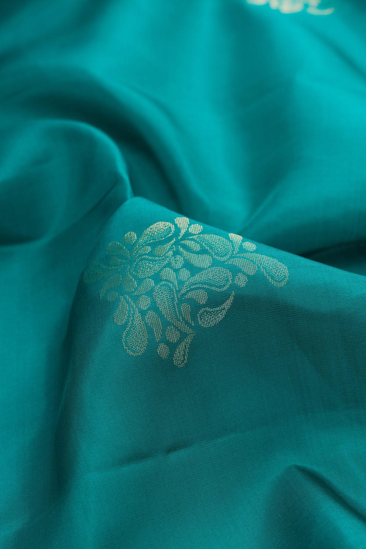 Close up of Pure Silk Teal Soft Saree with Zari Butta on the body and Zari Border.  displaying folds