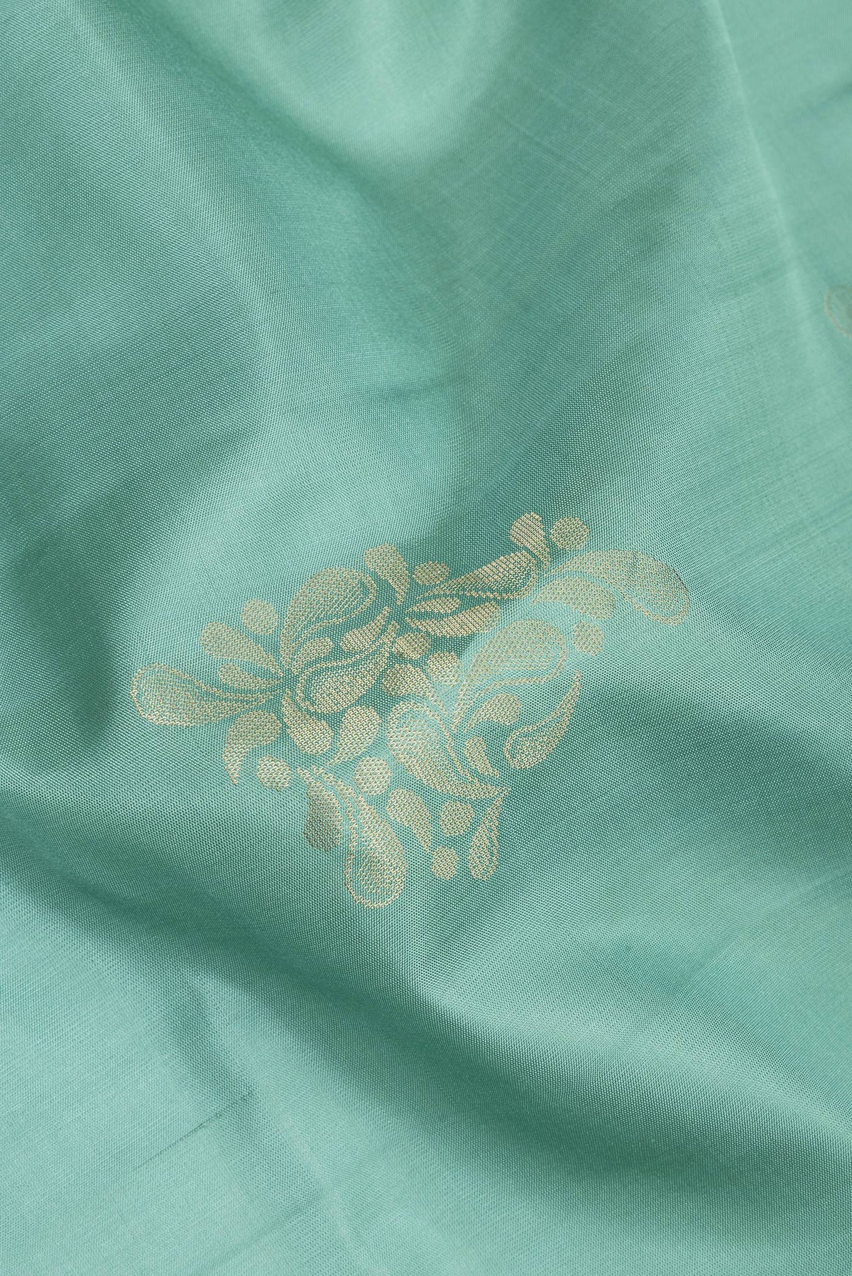 Close up of Pure Silk Sea Green Soft Saree with Zari Butta on the body and Zari Border.  displaying folds