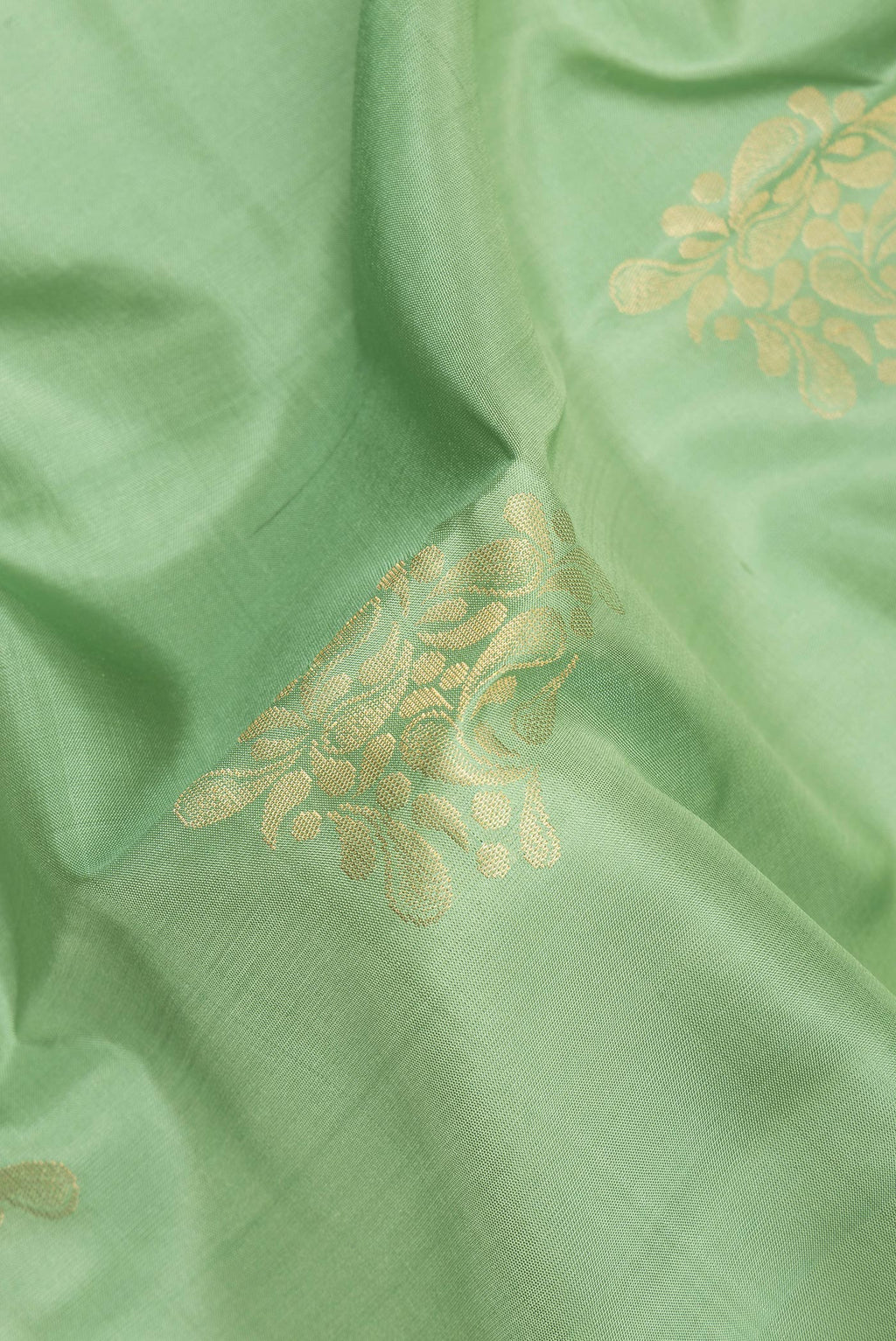Close up of Pure Silk Pista Green Soft Saree with Zari Butta on the body and Zari Border.  displaying folds