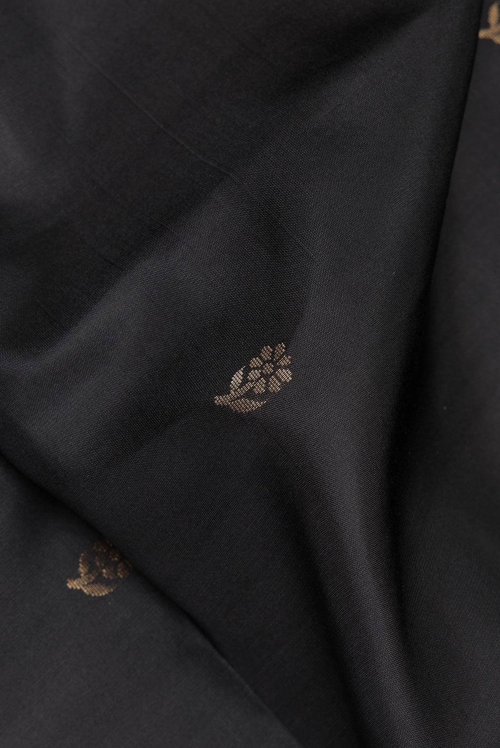 Close up of Pure Silk Black Soft Saree with Zari Butta on the body and Zari Border.  displaying folds