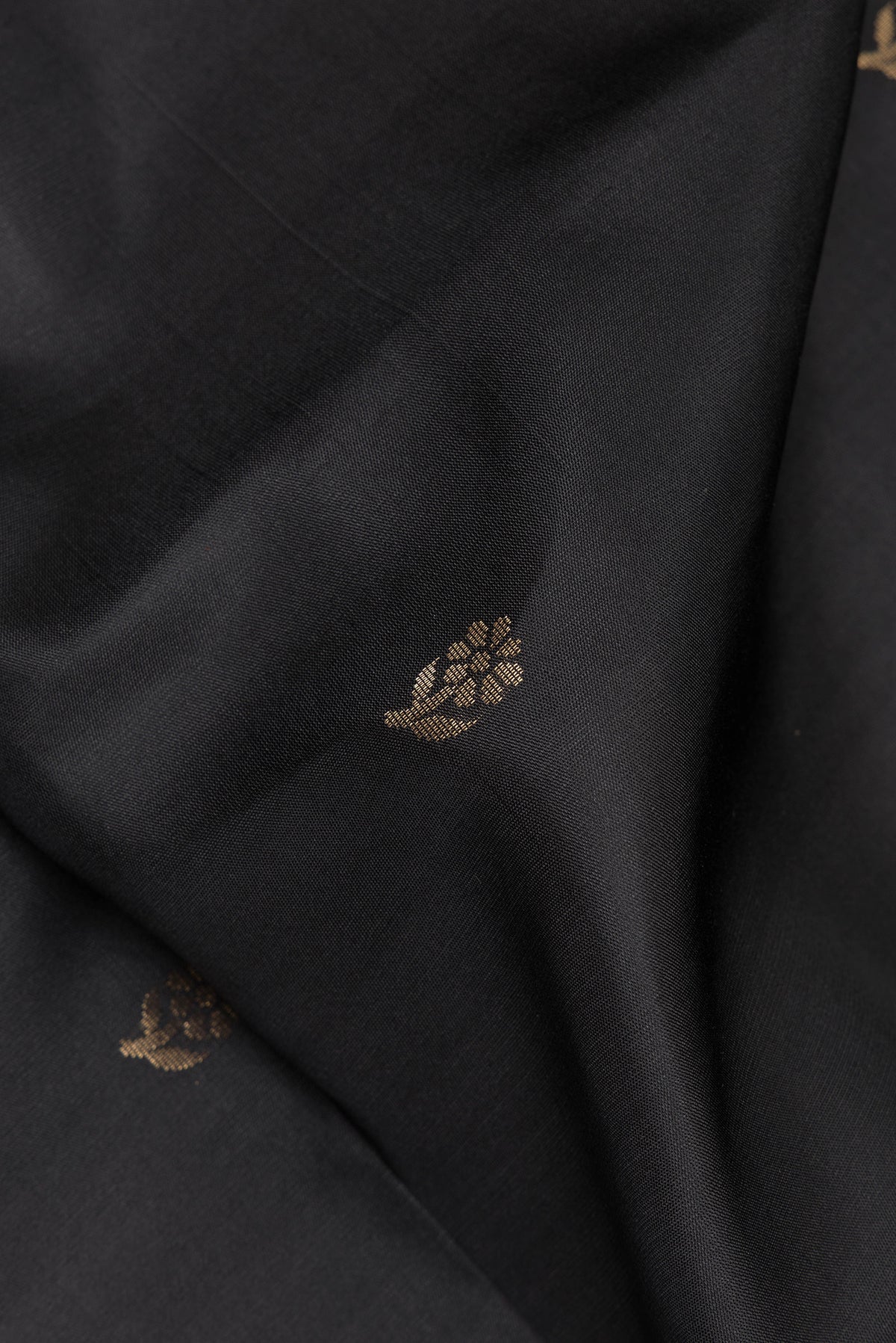 Close up of Pure Silk Black Soft Saree with Zari Butta on the body and Zari Border.  displaying folds