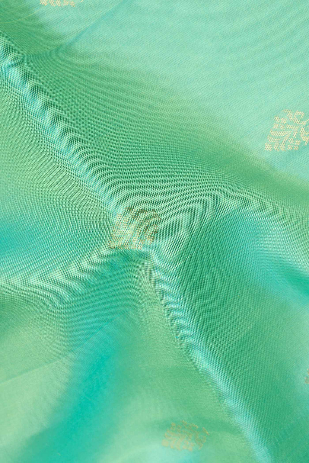 Close up of Pure Silk Sea Green Dual Tone Soft Saree with Zari Butta on the body and Zari Border.  displaying folds