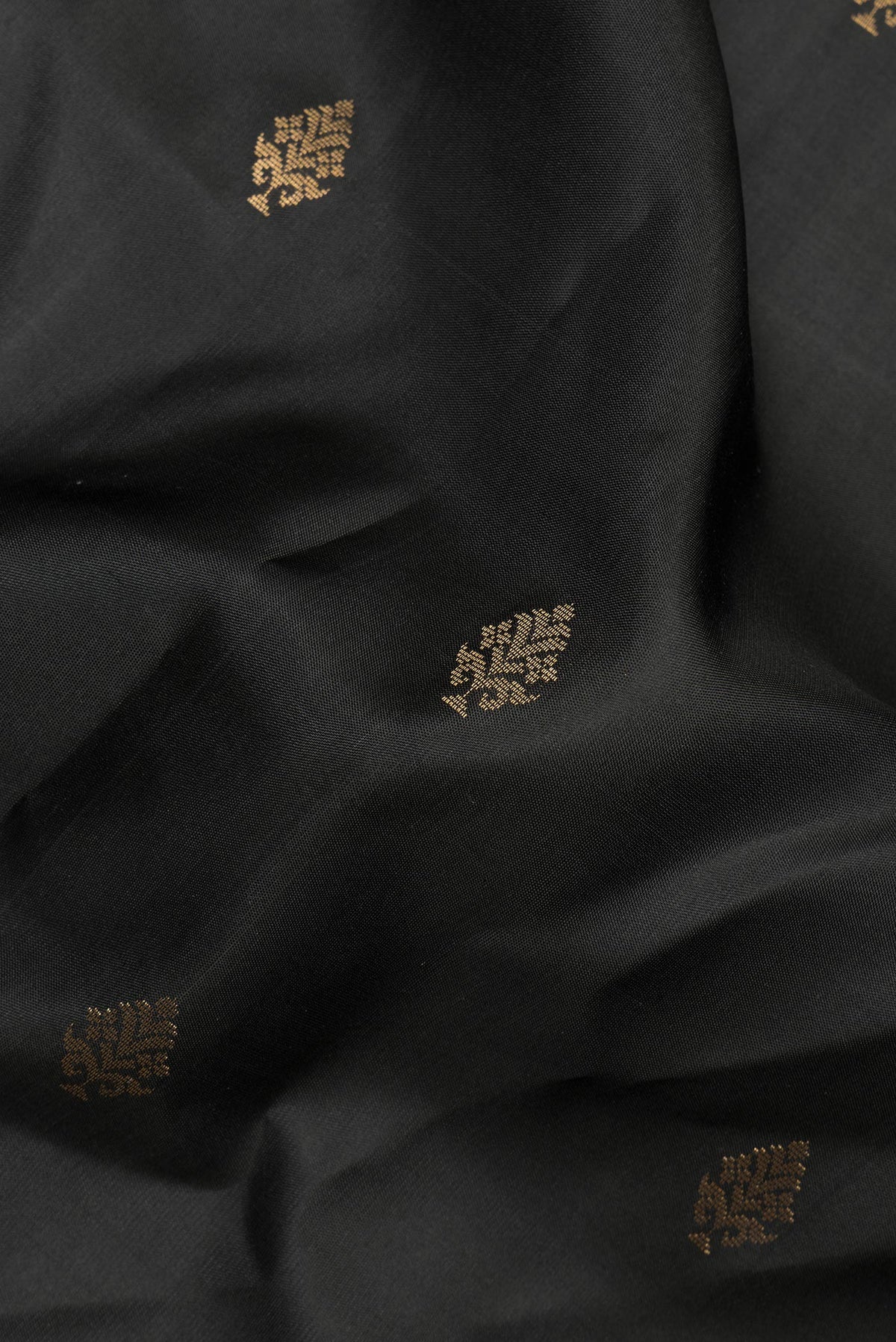 Close up of Pure Silk Black Soft Saree with Zari Butta on the body and Zari Border.  displaying folds