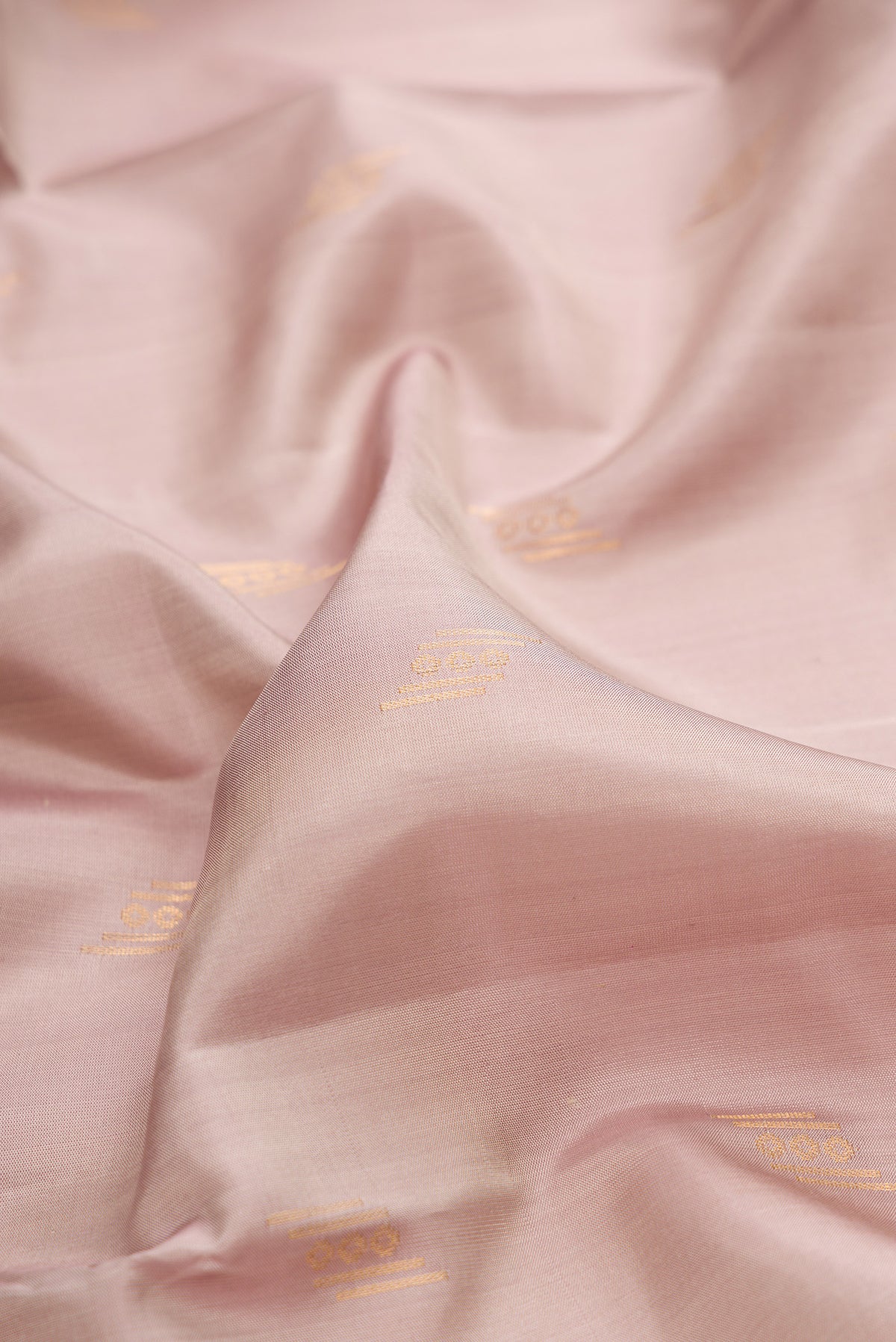 Close up of Pure Silk Rose Gold Soft Saree with Zari Butta on the body and Zari Border.  displaying folds