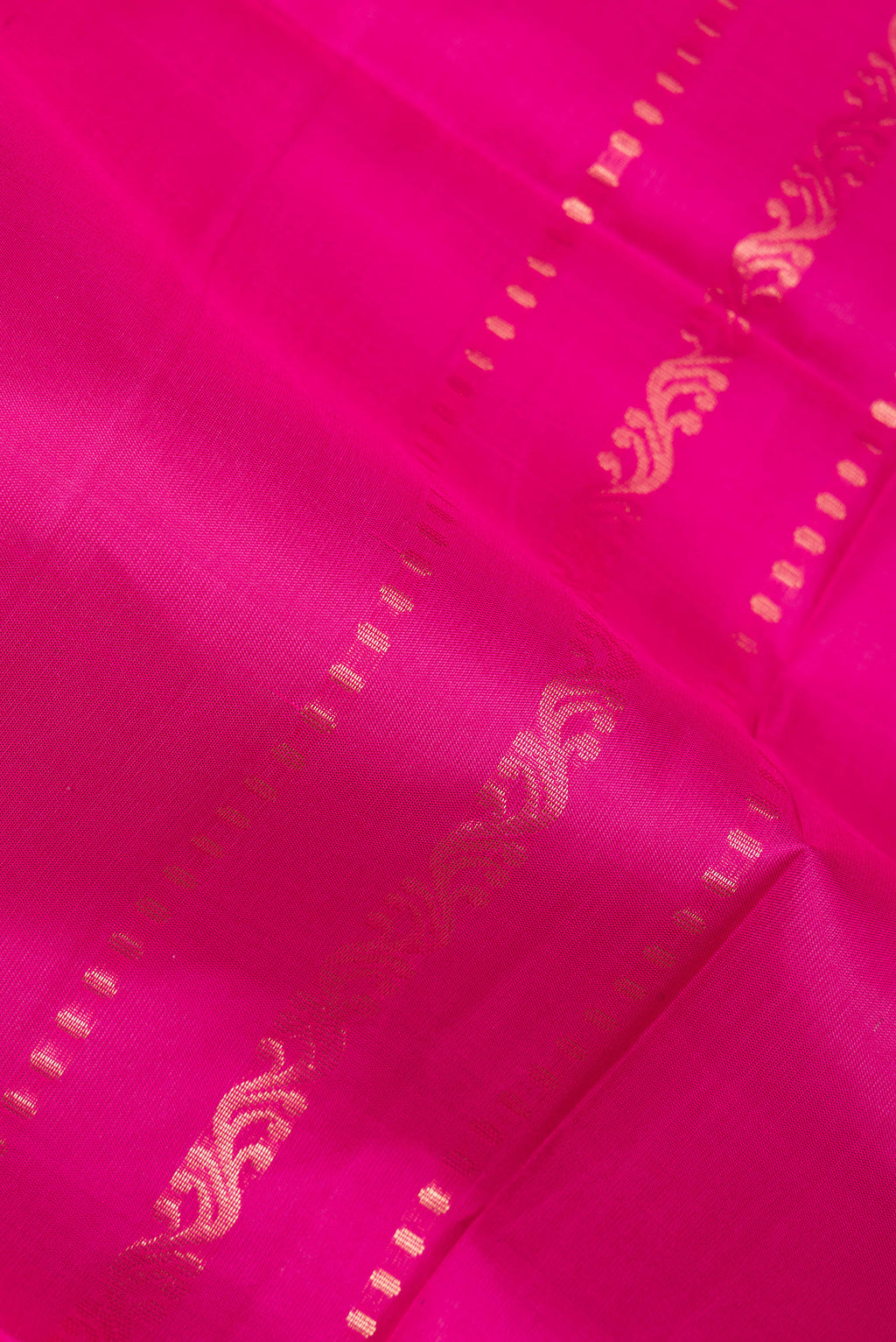Close up of Pure Silk Dark Pink Soft Saree with Zari Butta on the body and Zari Border.  displaying folds