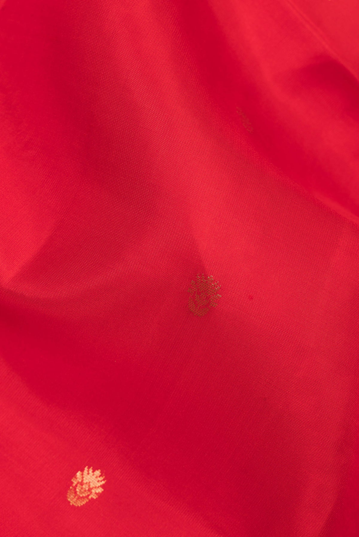 Close up of Pure Silk Red Soft Saree with Zari Butta on the body and Zari Border.  displaying folds