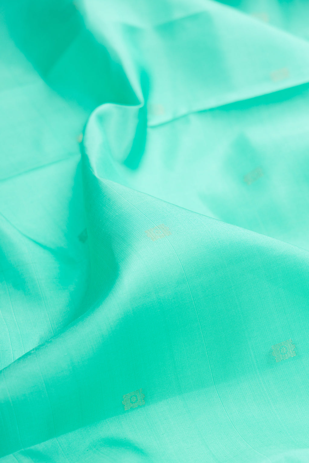Close up of Pure Silk Sea Green Soft Saree with Zari Butta on the body and Fancy Border.  displaying folds