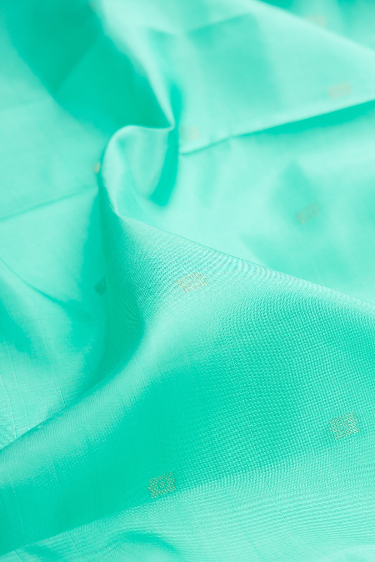 Close up of Pure Silk Sea Green Soft Saree with Zari Butta on the body and Fancy Border.  displaying folds