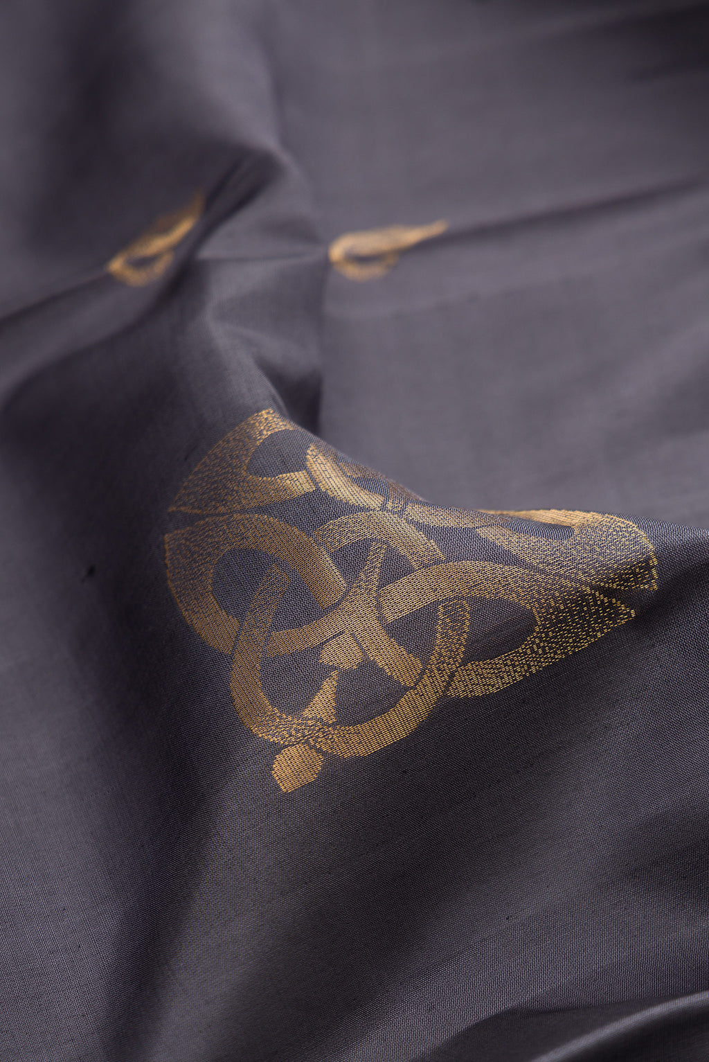 Close up of Pure Silk Grey Soft Saree with Zari Butta on the body and Zari Border.  displaying folds