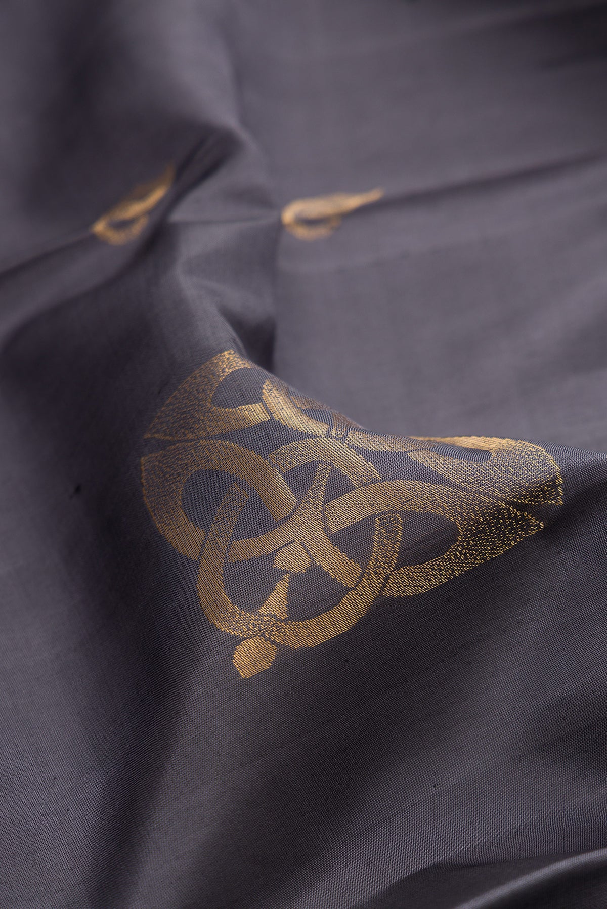 Close up of Pure Silk Grey Soft Saree with Zari Butta on the body and Zari Border.  displaying folds