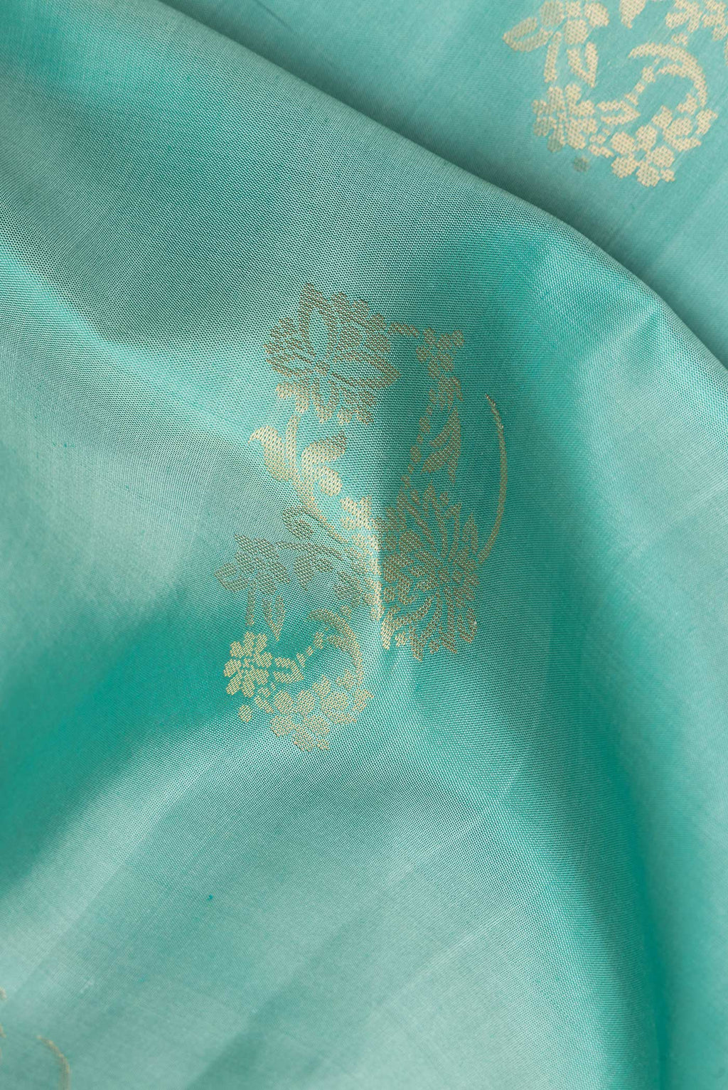 Close up of Pure Silk Light Green Soft Saree with Zari Butta on the body and Zari Border.  displaying folds