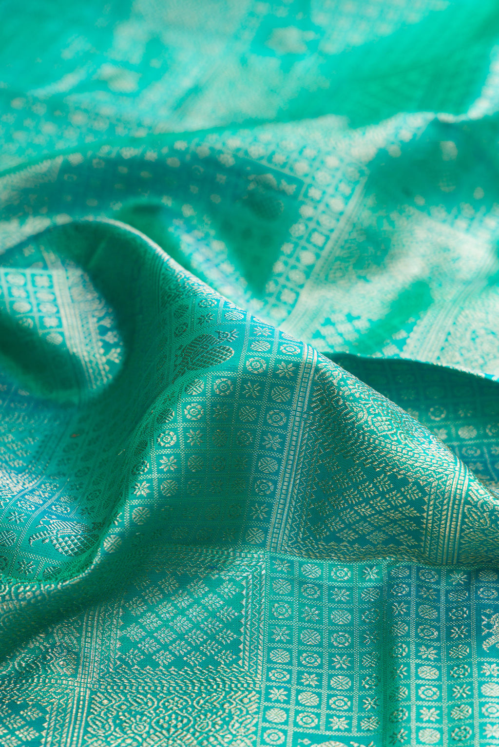Close up of Pure Silk Turquoise Dual Tone Kanjivaram Saree with Zari Brocade on the body and Fancy Border.  displaying folds