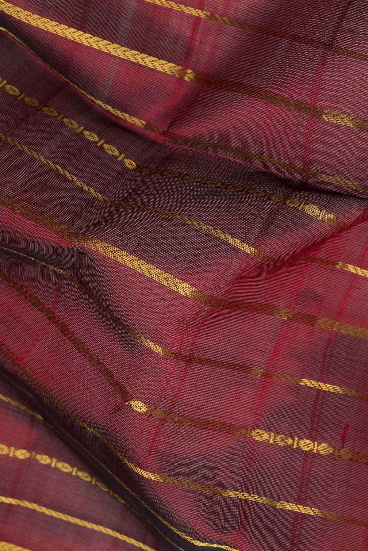 Close up of Maroon Silk Cotton Saree with Stripes on the body and Zari Border.  displaying folds