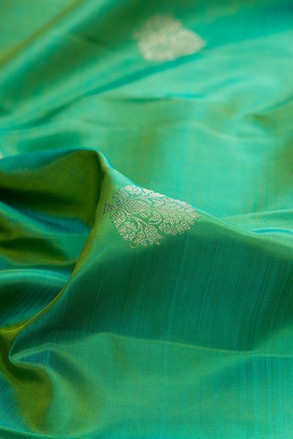 Close up of Pure Silk Green Dual Tone Kanjivaram Saree with Zari Butta on the body and Fancy Border.  displaying folds