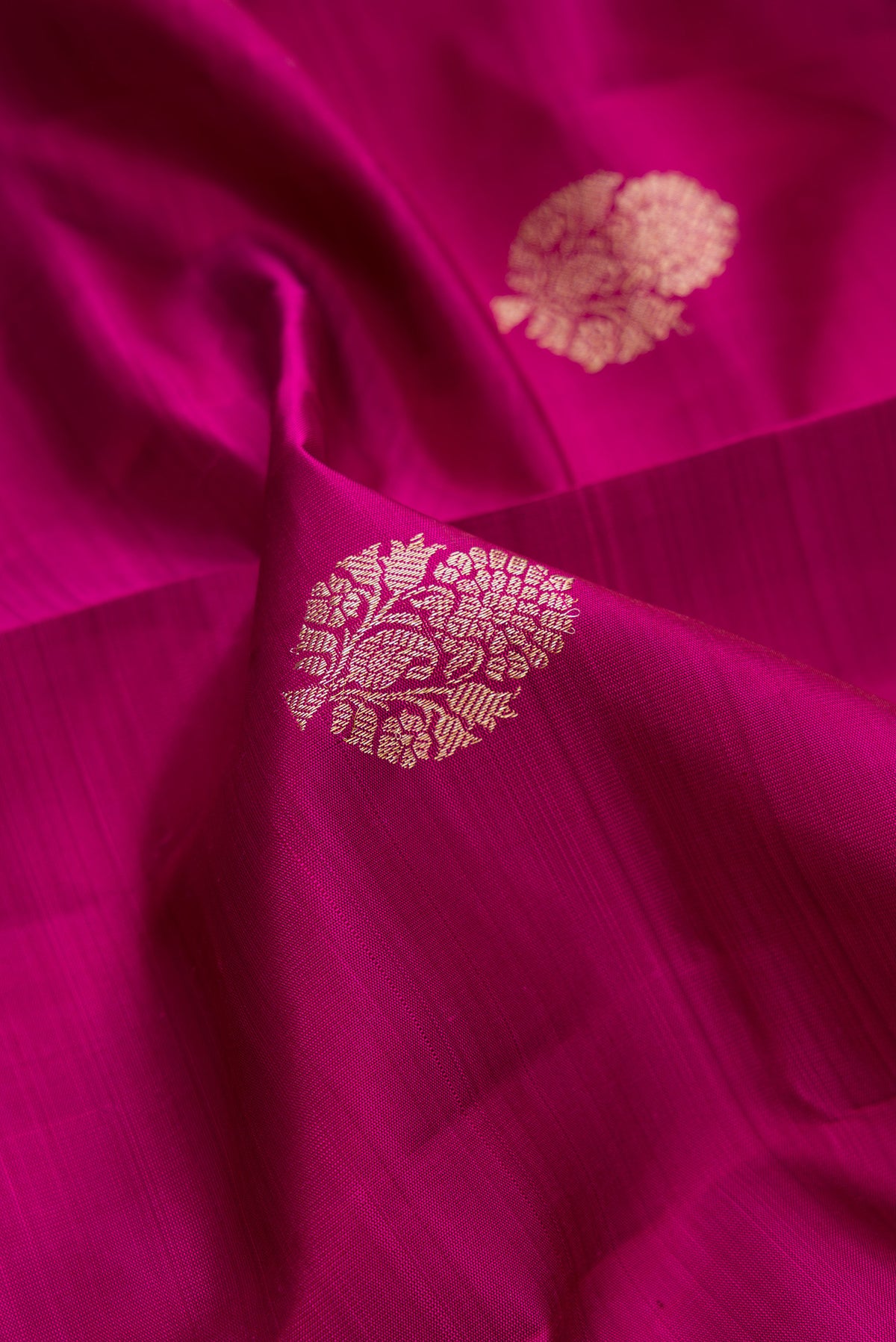 Close up of Pure Silk Magenta Dual Tone Kanjivaram Saree with Zari Butta on the body and Fancy Border.  displaying folds