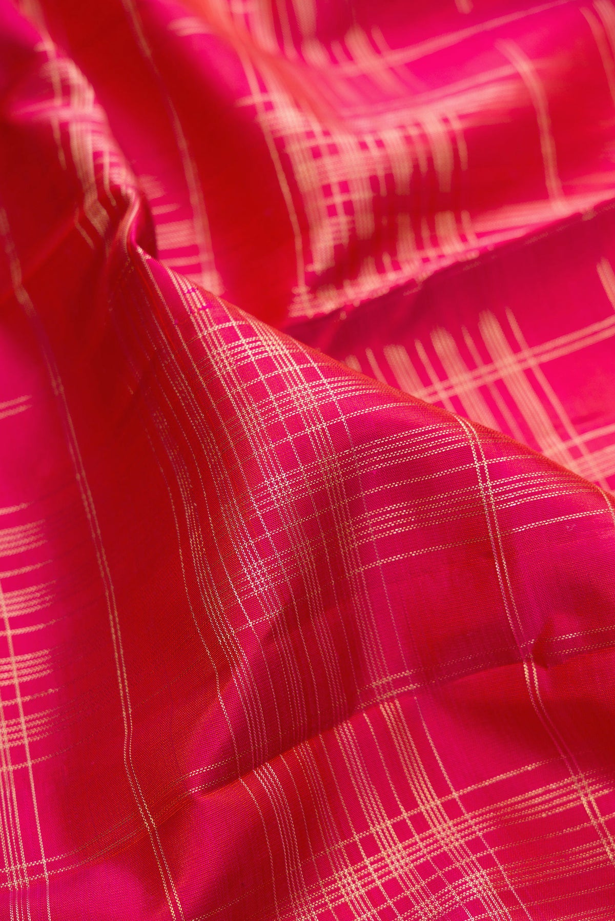 Close up of Pure Silk Dark Pink Kanchipuram Saree with Checked design on the body and Zari Border.  displaying folds