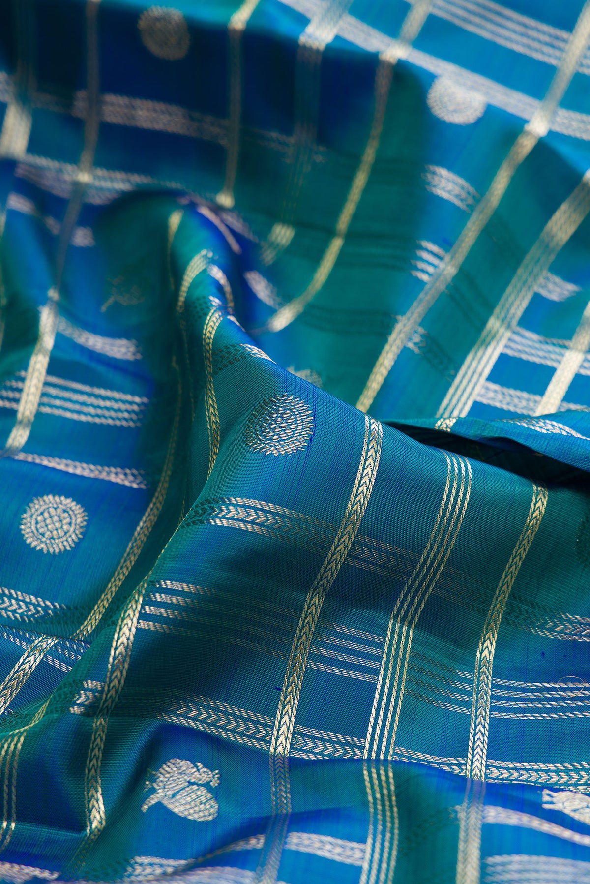 Close up of Pure Silk Peacock Blue Dual Tone Kanchipuram Saree with Checked design on the body and Zari Border.  displaying folds