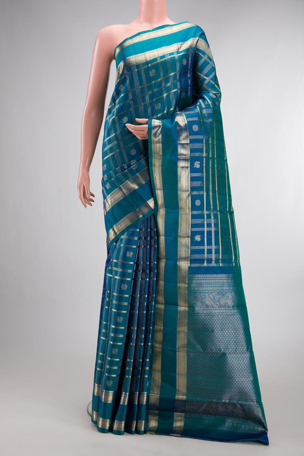 Pure Silk Peacock Blue Dual Tone Kanchipuram Saree with Checked design on the body and Zari Border.  displayed on a mannequin