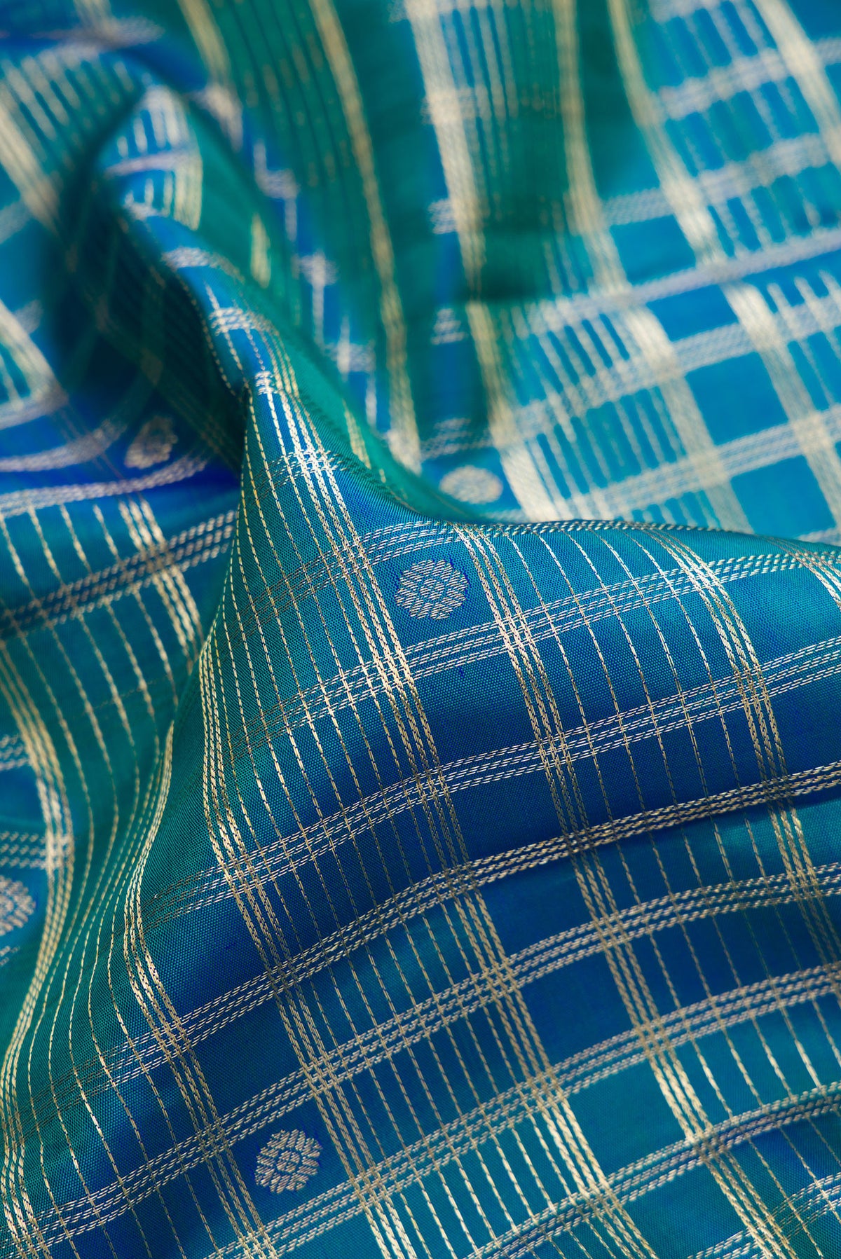 Close up of Pure Silk Peacock Blue Dual Tone Kanchipuram Saree with Checked design on the body and Zari Border.  displaying folds
