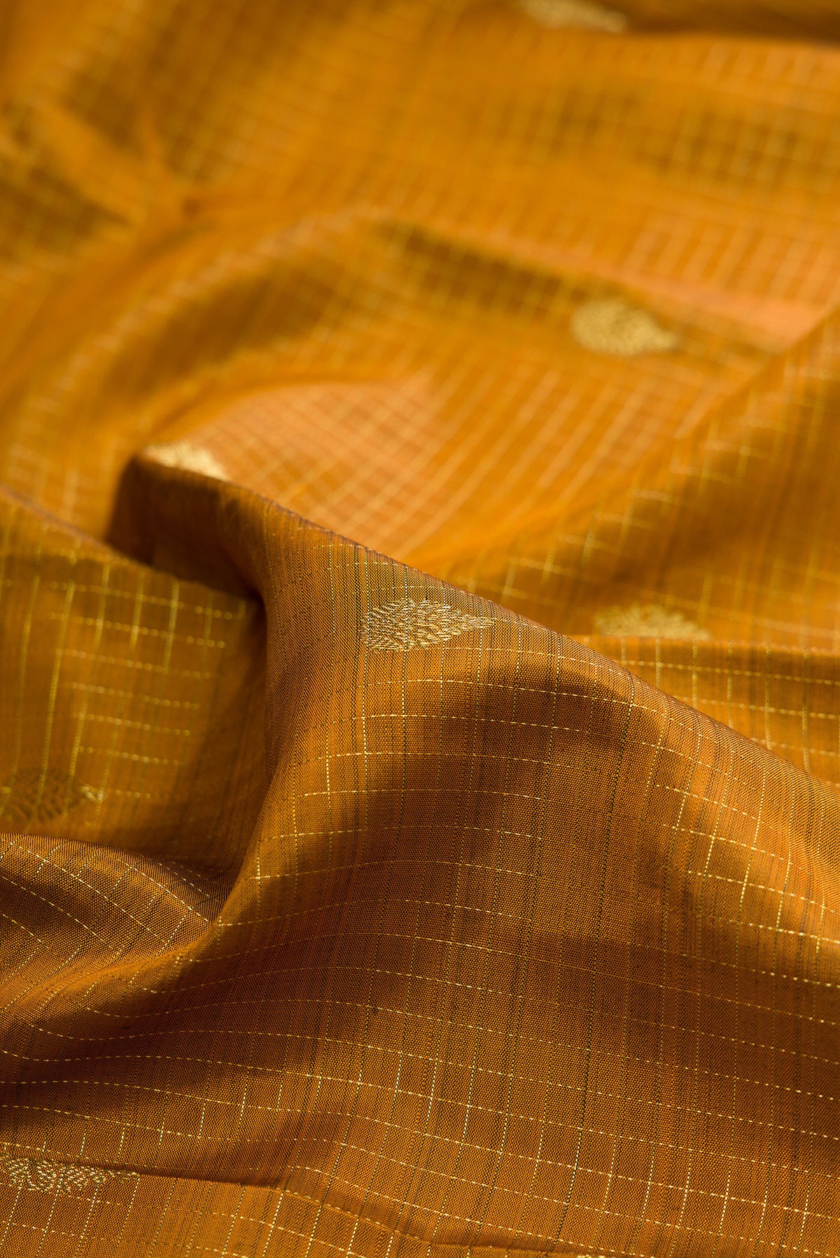 Close up of Pure Silk Mustard Kanchipuram Saree with Checked design on the body and Zari Border.  displaying folds