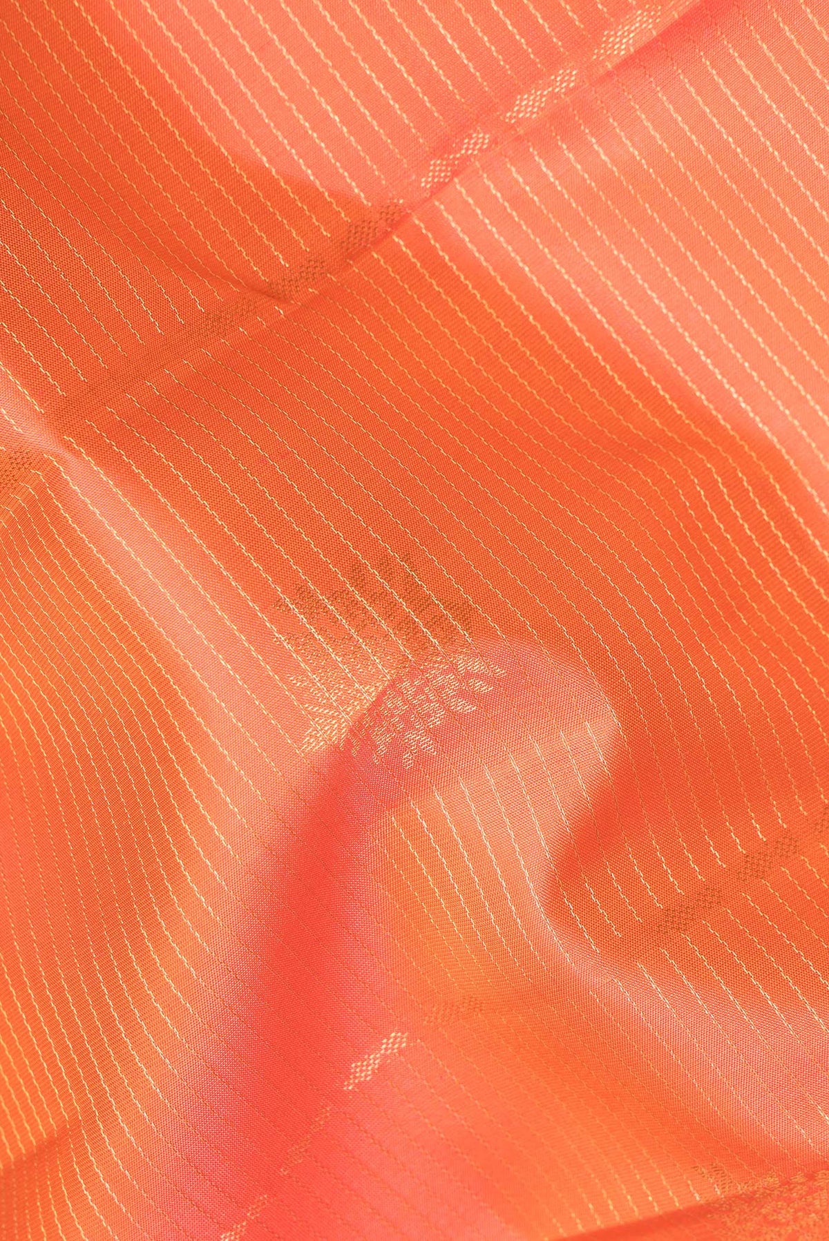 Close up of Pure Silk Brick Orange Dual Tone Kanchipuram Saree with Stripes on the body and Zari Border.  displaying folds