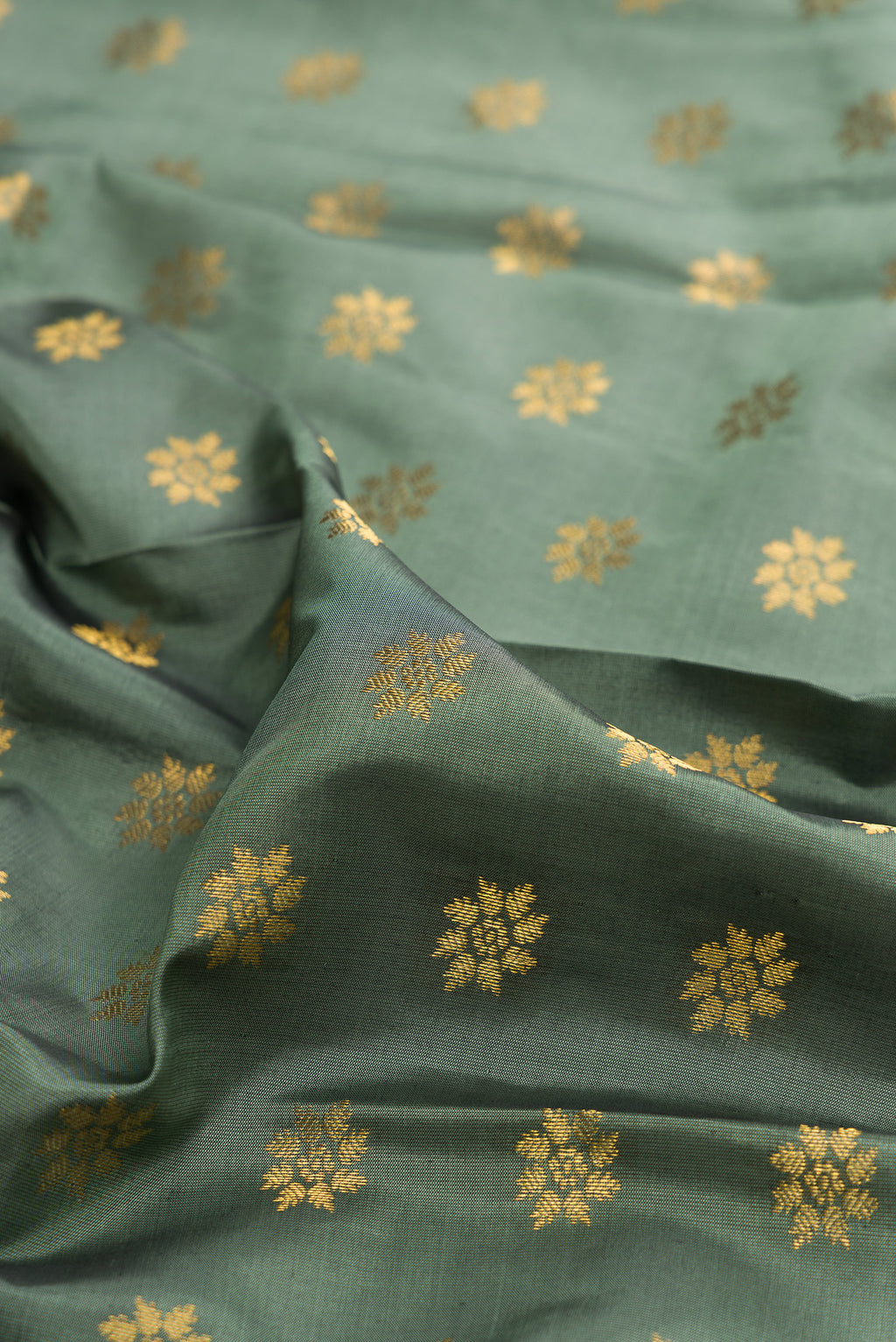 Close up of Pure Silk Olive Green Kanchipuram Saree with Zari Butta on the body and Zari Border.  displaying folds