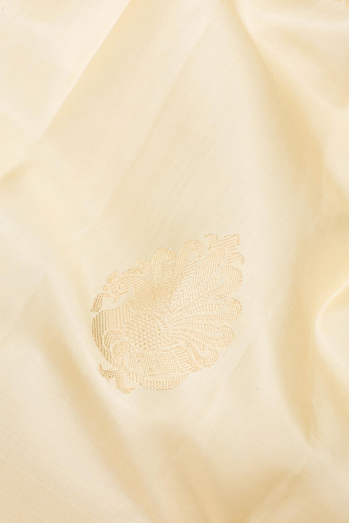 Close up of Pure Silk Cream Kanjivaram Saree with Zari Butta on the body and Zari Border.  displaying folds