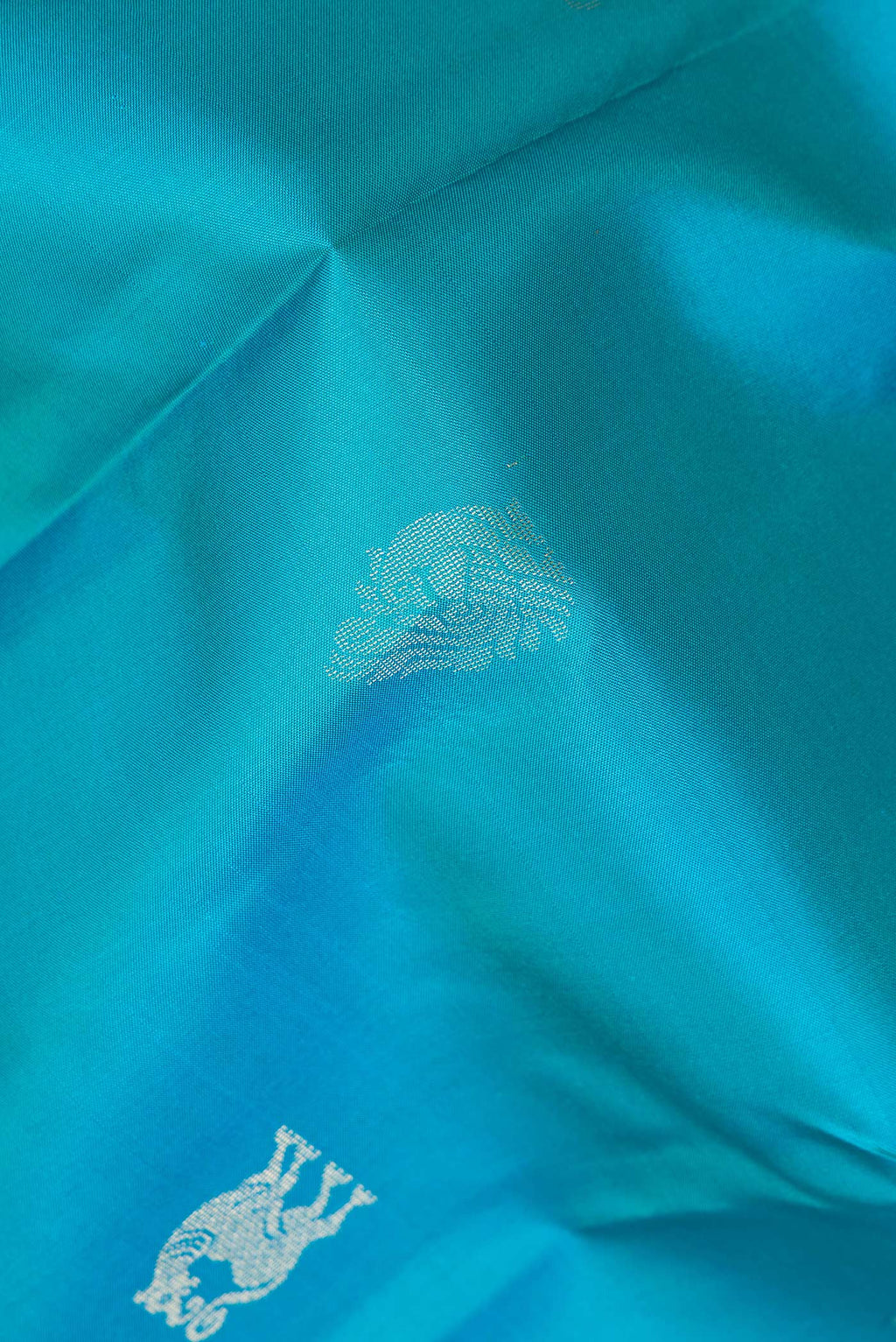 Close up of Pure Silk Peacock Blue Dual Tone Kanchipuram Saree with Zari Butta on the body and Zari Border.  displaying folds