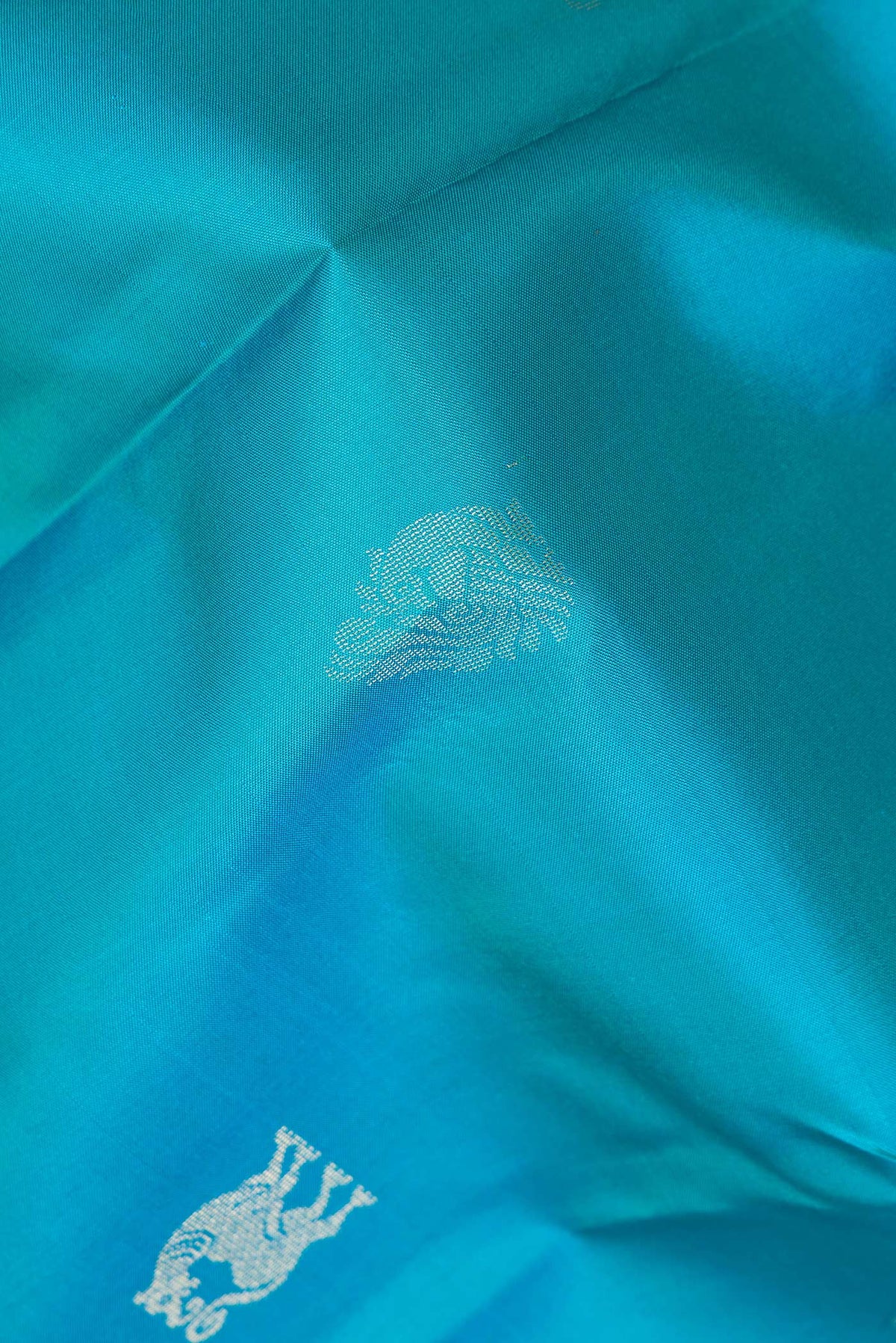 Close up of Pure Silk Peacock Blue Dual Tone Kanchipuram Saree with Zari Butta on the body and Zari Border.  displaying folds
