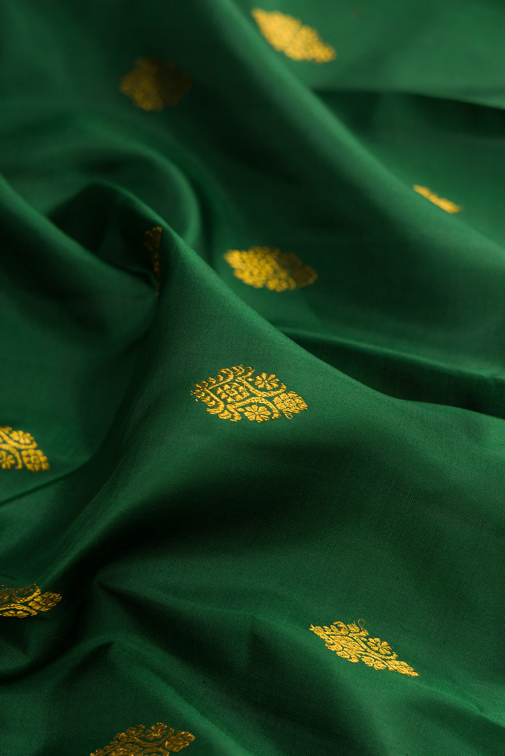 Close up of Pure Silk Bottle Green Kanjivaram Saree with Zari Butta on the body and Zari Border.  displaying folds