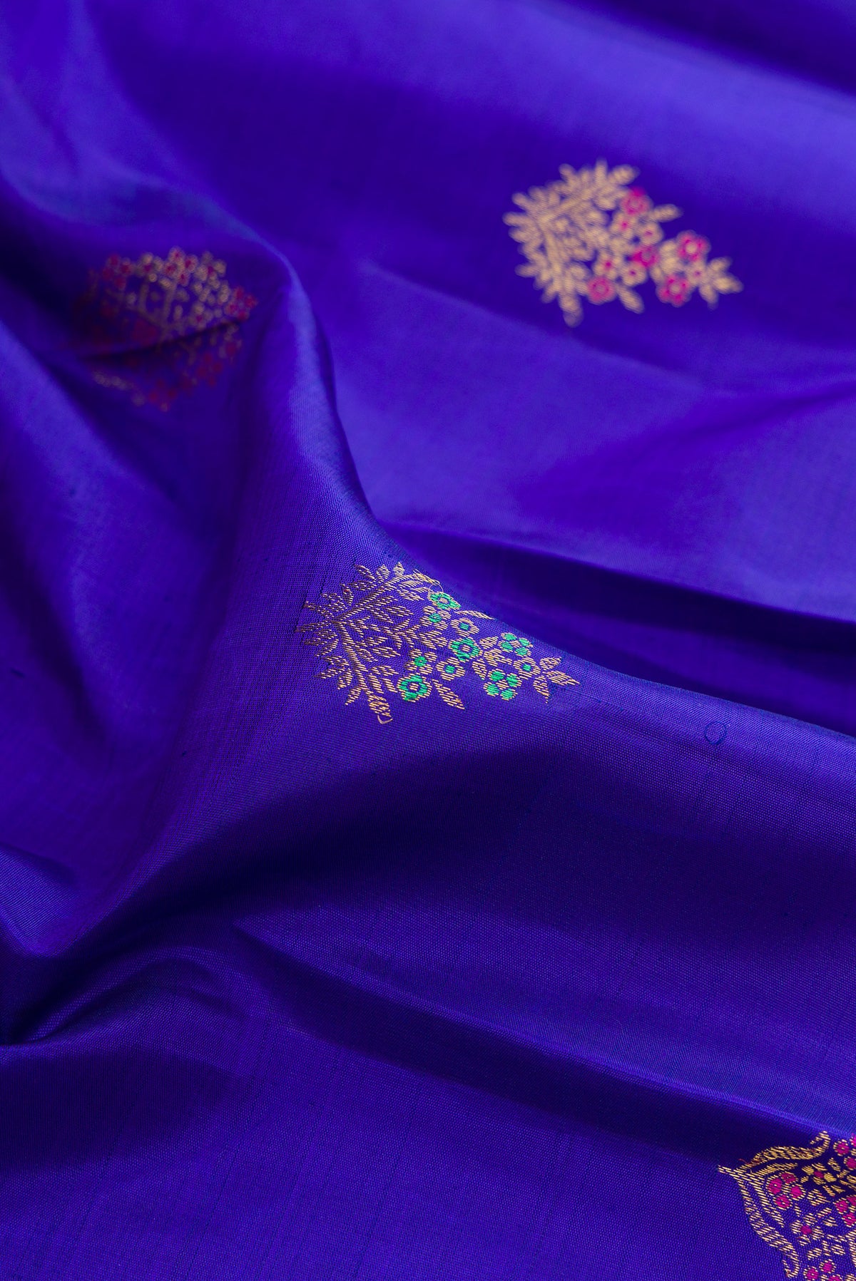 Close up of Pure Silk Royal Blue Kanjivaram Saree with Zari And Thread Butta on the body and Zari Border.  displaying folds