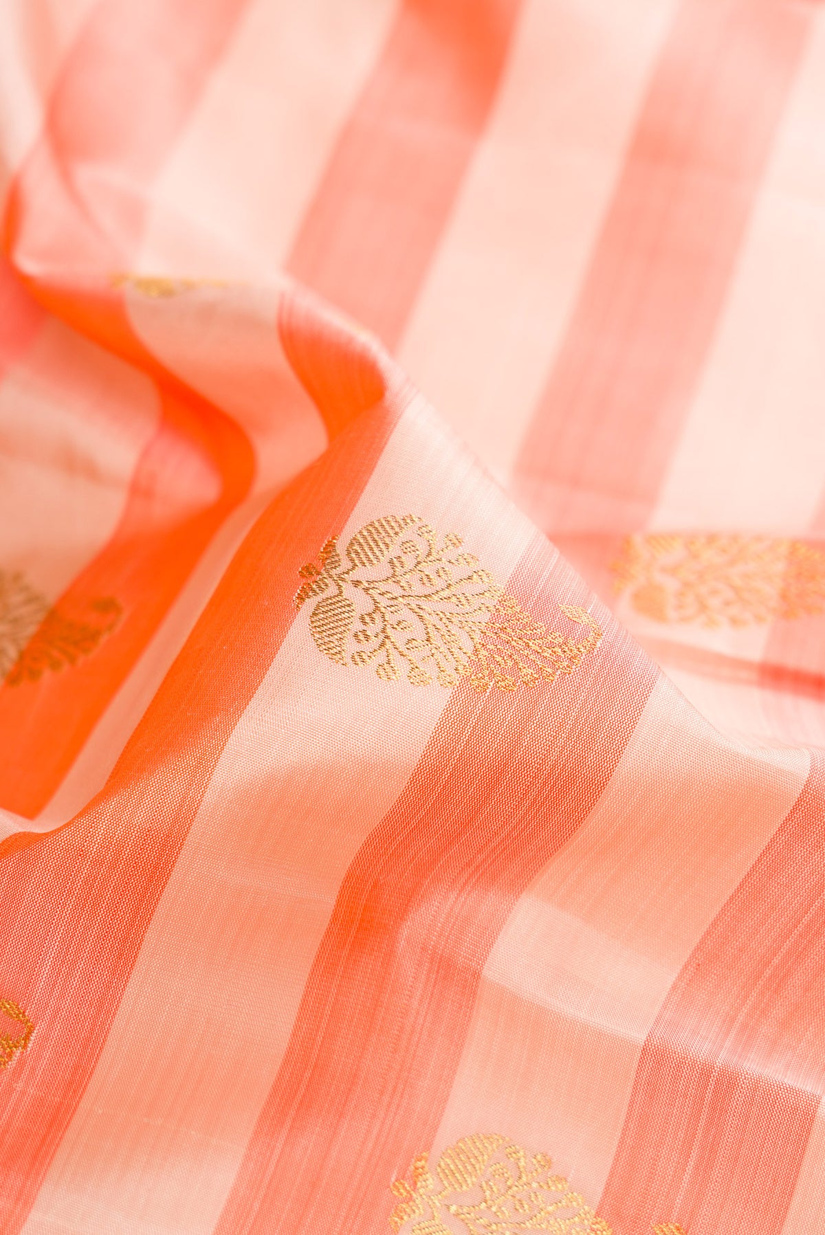 Close up of Pure Silk Beige and Peach Color Kanjivaram Saree with Stripes on the body and Zari Border.  displaying folds