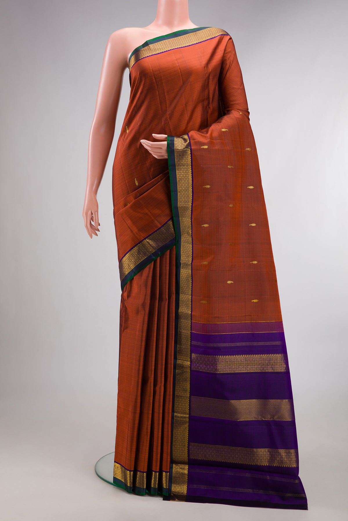 Pure Silk Rust Kanchipuram Saree with Zari Butta on the body and Zari Border.  displayed on a mannequin