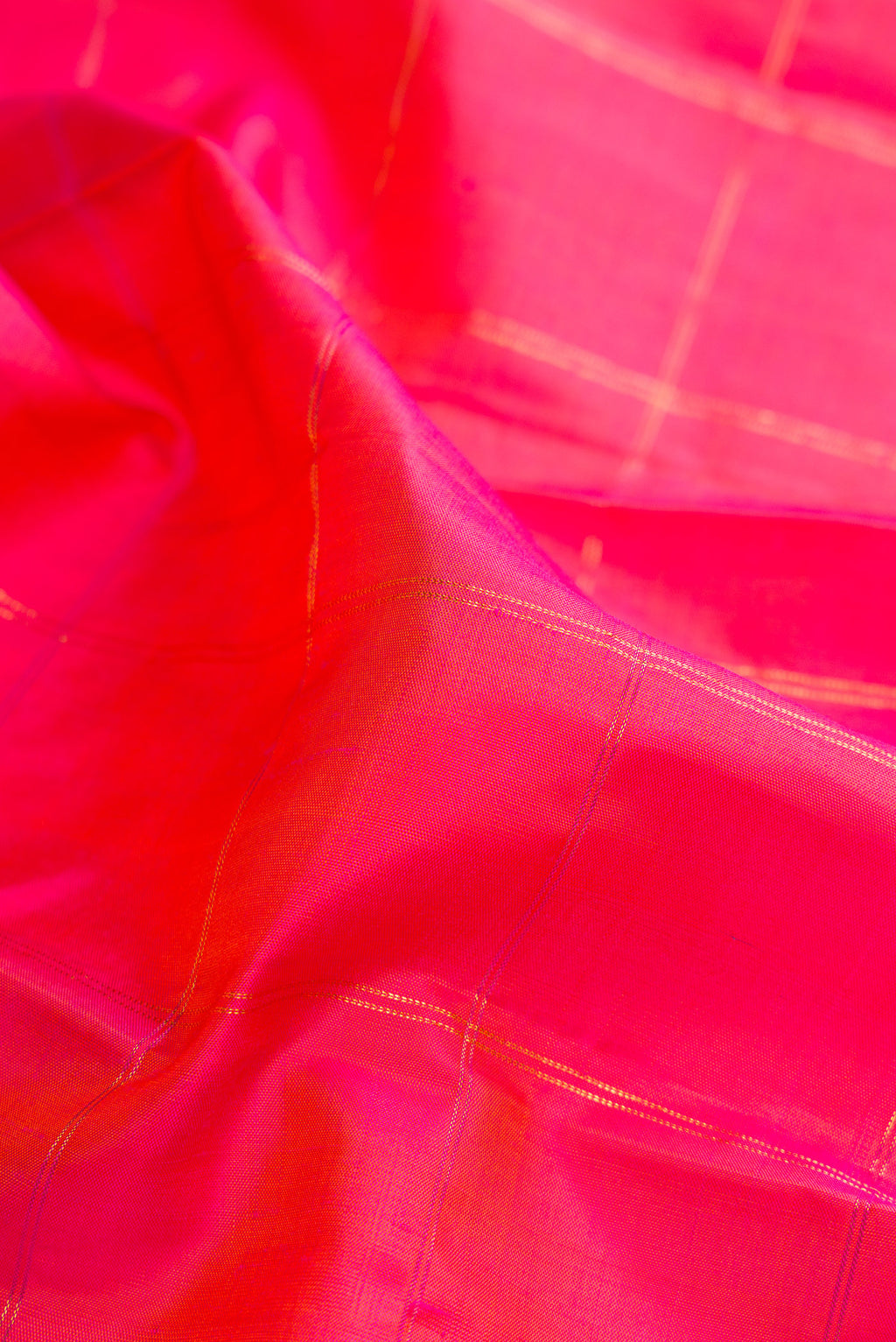 Close up of Pure Silk Coral Kanchipuram Saree with Checked design on the body and Plain Border.  displaying folds