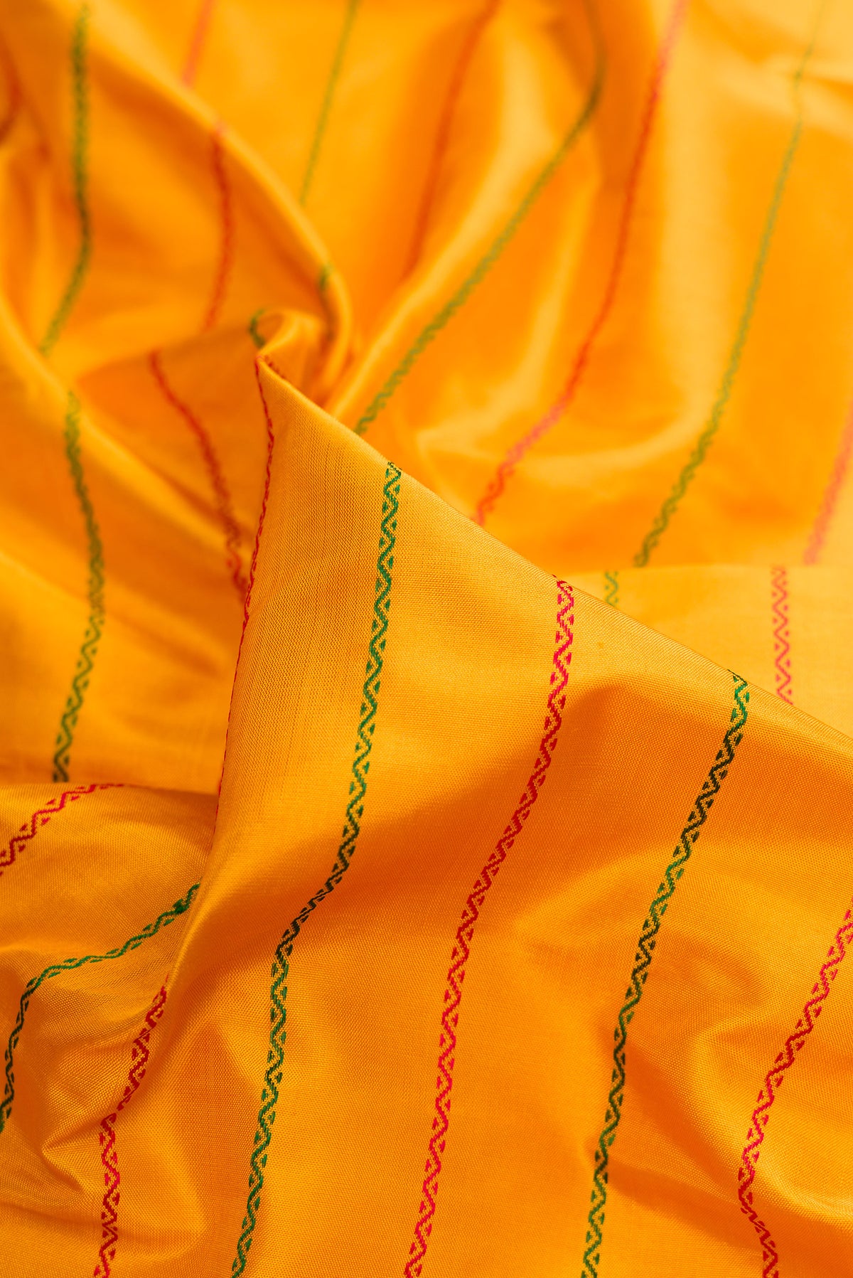 Close up of Pure Silk Mustard Kanjivaram Saree with Veldhari on the body and Zari Border.  displaying folds