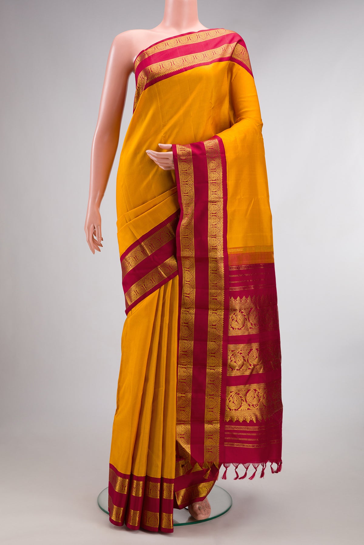 Pure Silk Mustard Kanjivaram Saree with Plain Body and Zari Border.  displayed on a mannequin