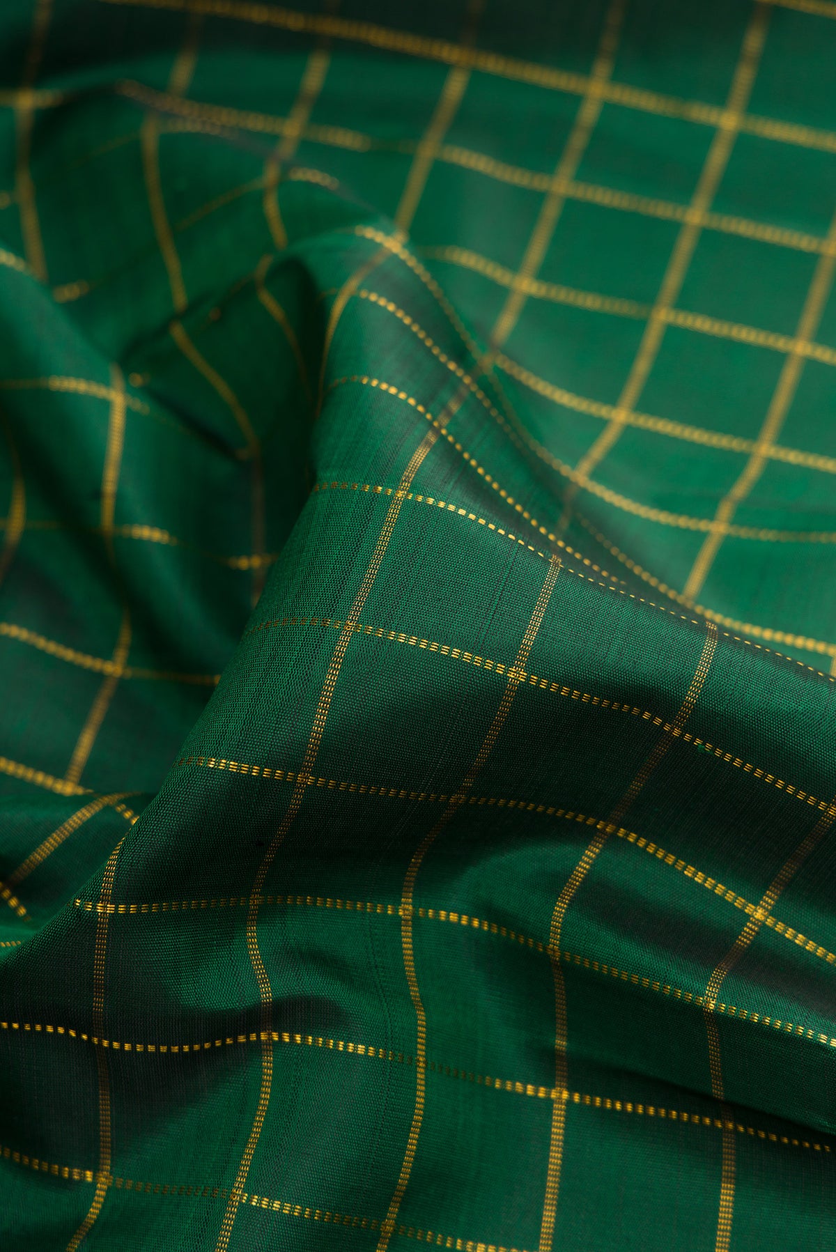 Close up of Pure Silk Bottle Green Kanchipuram Saree with Checked design on the body and Zari Border.  displaying folds