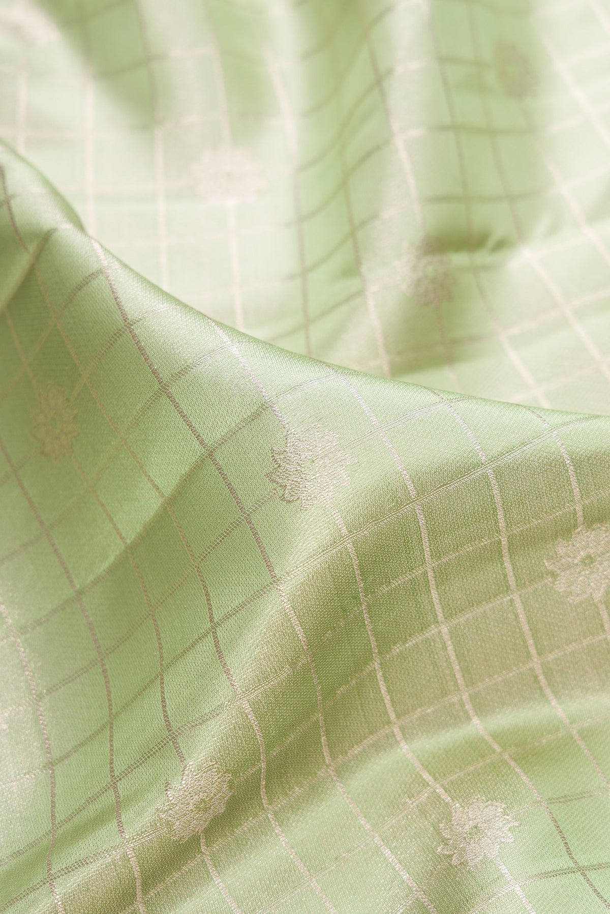 Close up of Pista Green Kanchipuram Tissue Saree with Checked design on the body and Fancy Border.  displaying folds