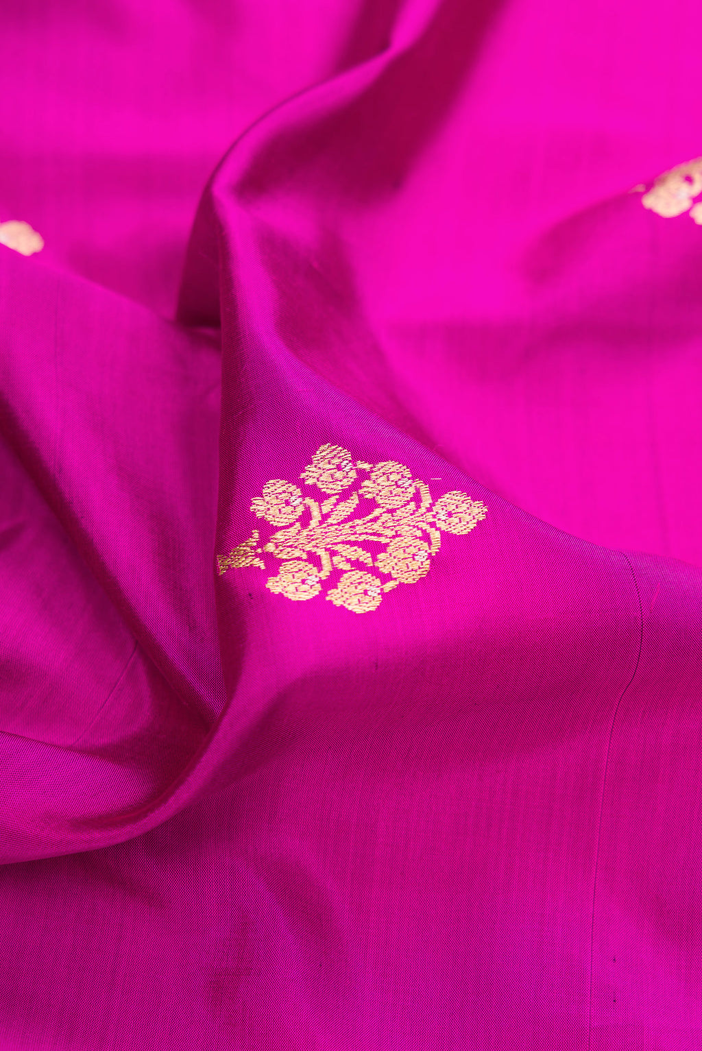 Close up of Pure Silk Rani Pink Banarasi Saree with Zari Butta on the body and Zari Border.  displaying folds