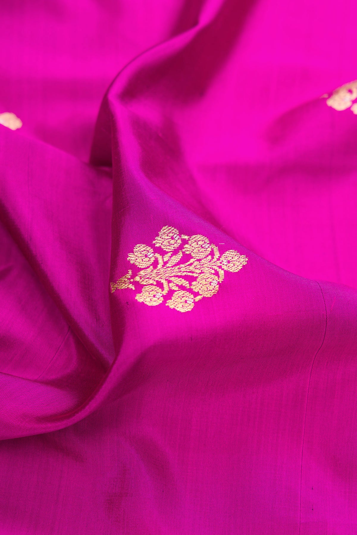 Close up of Pure Silk Rani Pink Banarasi Saree with Zari Butta on the body and Zari Border.  displaying folds
