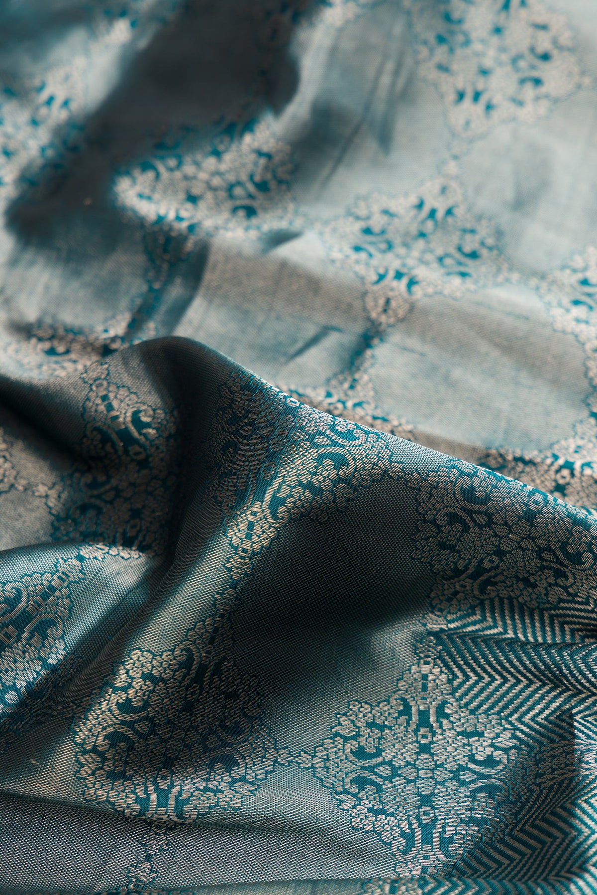 Close up of Pure Silk Peacock Blue Banarasi Saree with Zari Butta on the body and Zari Border.  displaying folds