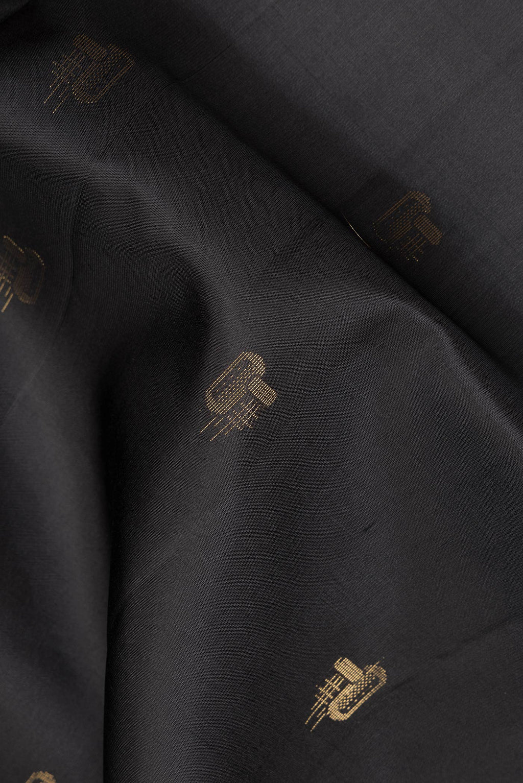 Close up of Pure Silk Black Soft Saree with Zari Butta on the body and Zari Border.  displaying folds