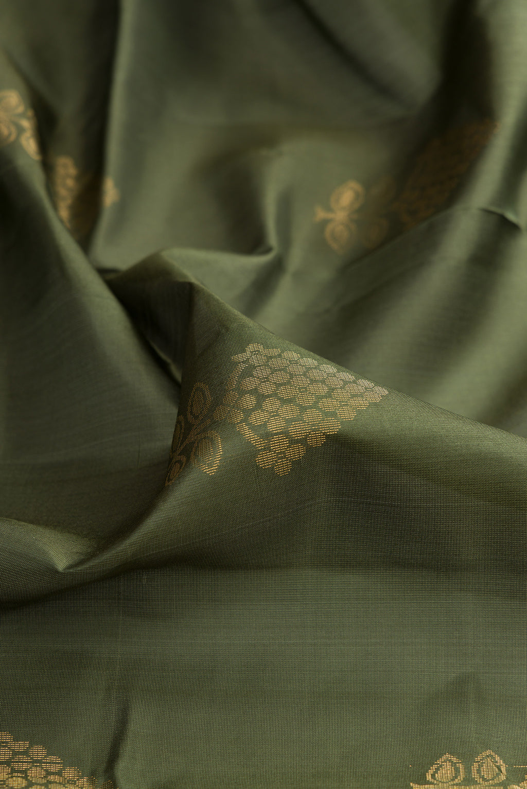 Close up of Pure Silk Mehandi Green Soft Saree with Zari Butta on the body and Zari Border.  displaying folds